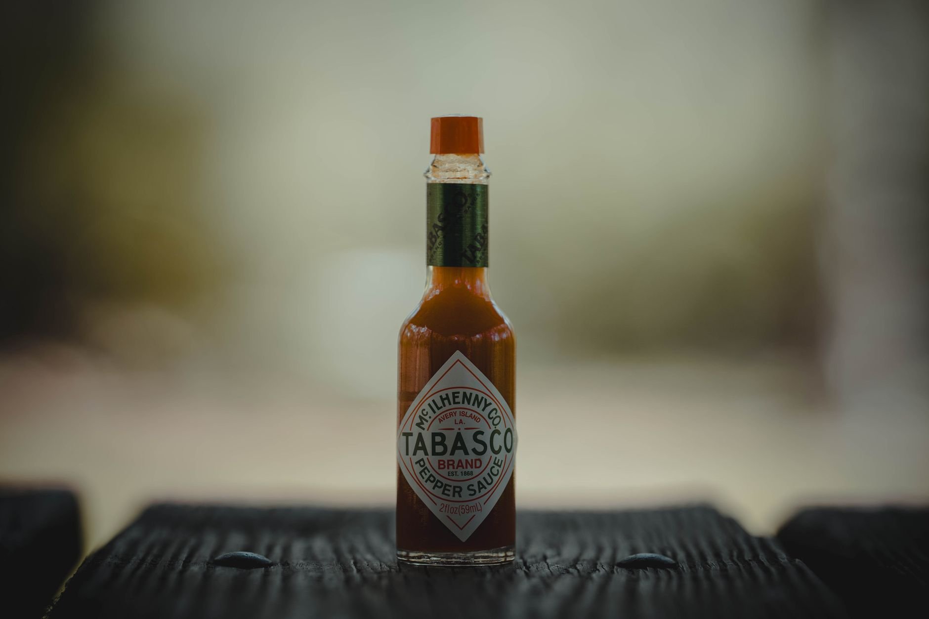 Artisan hot sauce bottle resting on a wooden surface in warm natural light