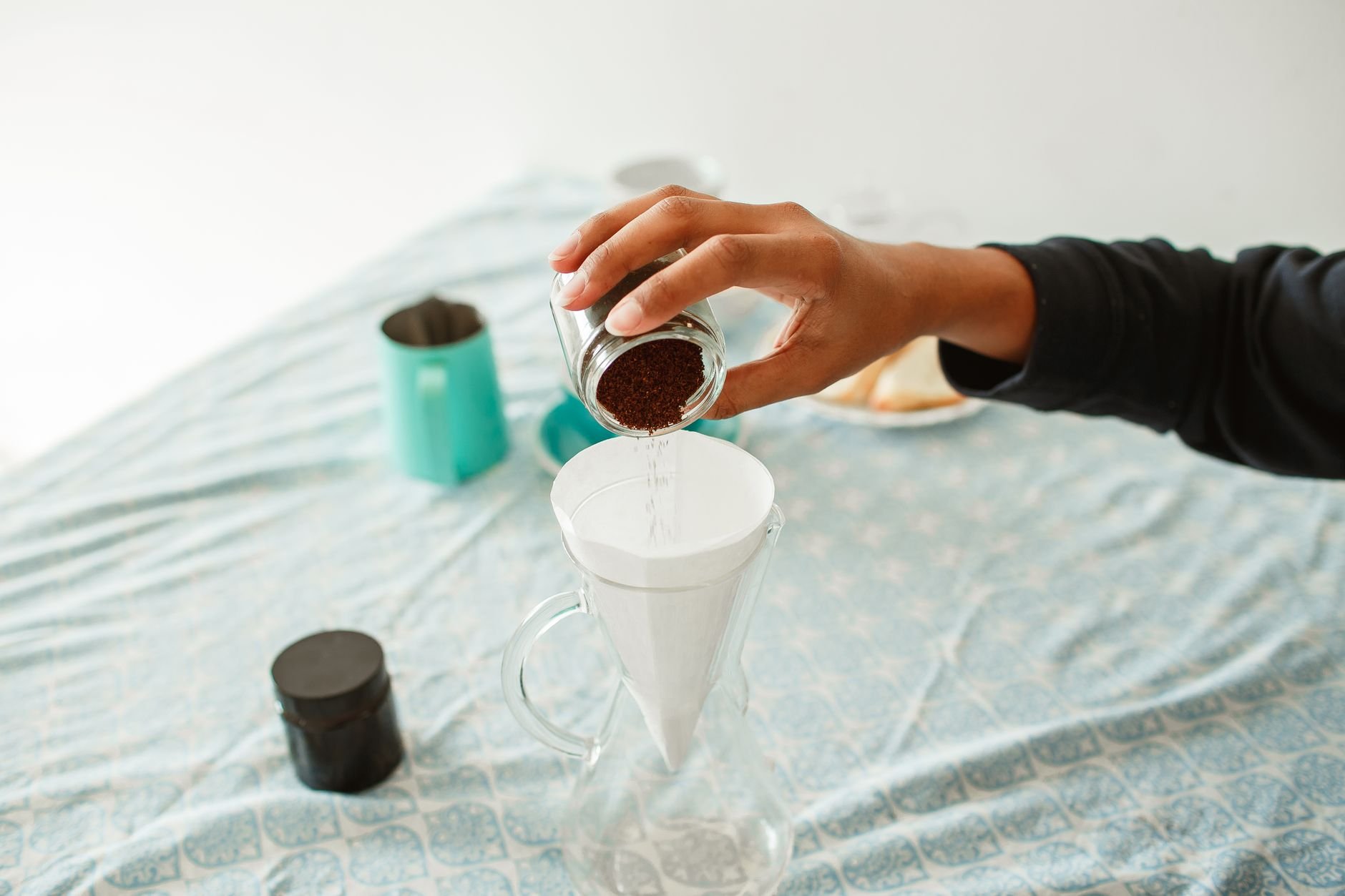 Hand pouring from a small-batch preparation in a warm kitchen setting